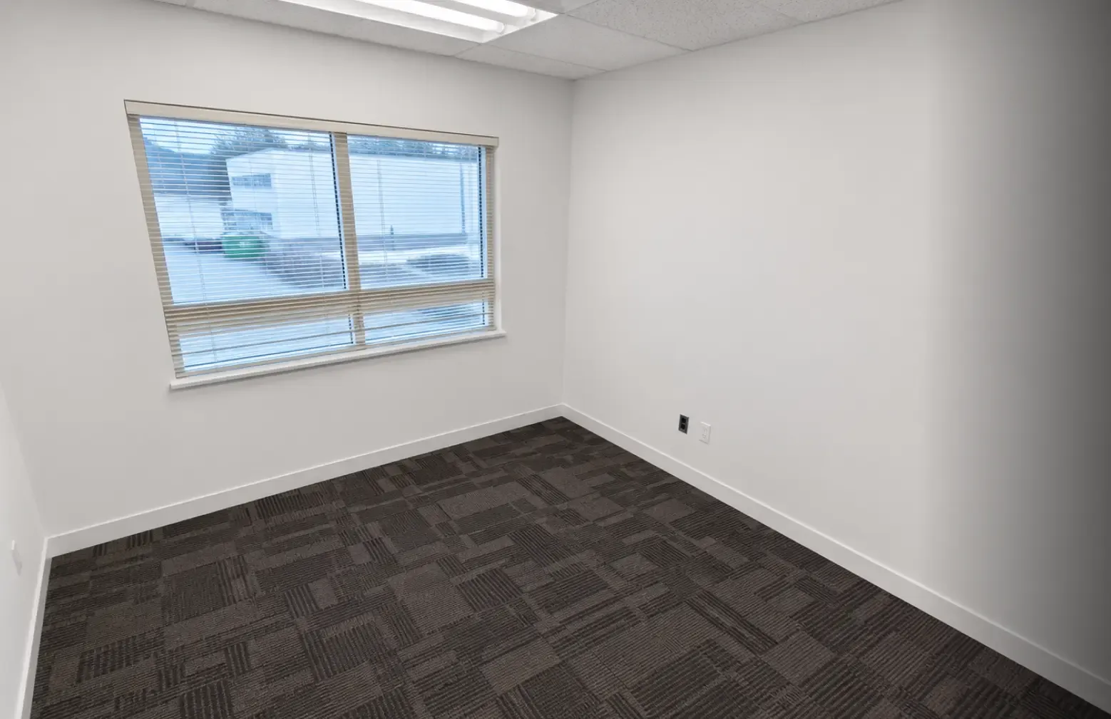 Completed commercial private office remodel featuring fresh white walls, updated trim, and new modern patterned carpet, completed by Pacific Coast Contracting (PCC).